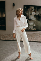 a lady wears a white loose fit shirt with white suit pants